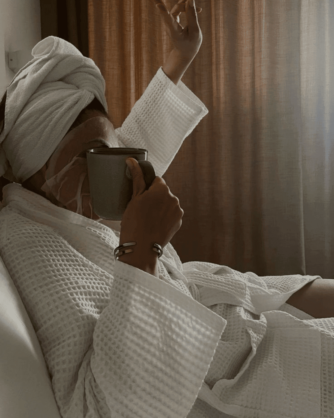 Relaxing in a robe with a face mask and hot drink in hand.